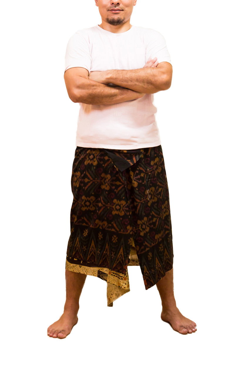 A man wearing a white shirt and brown traditional costume standing with his arms crossed