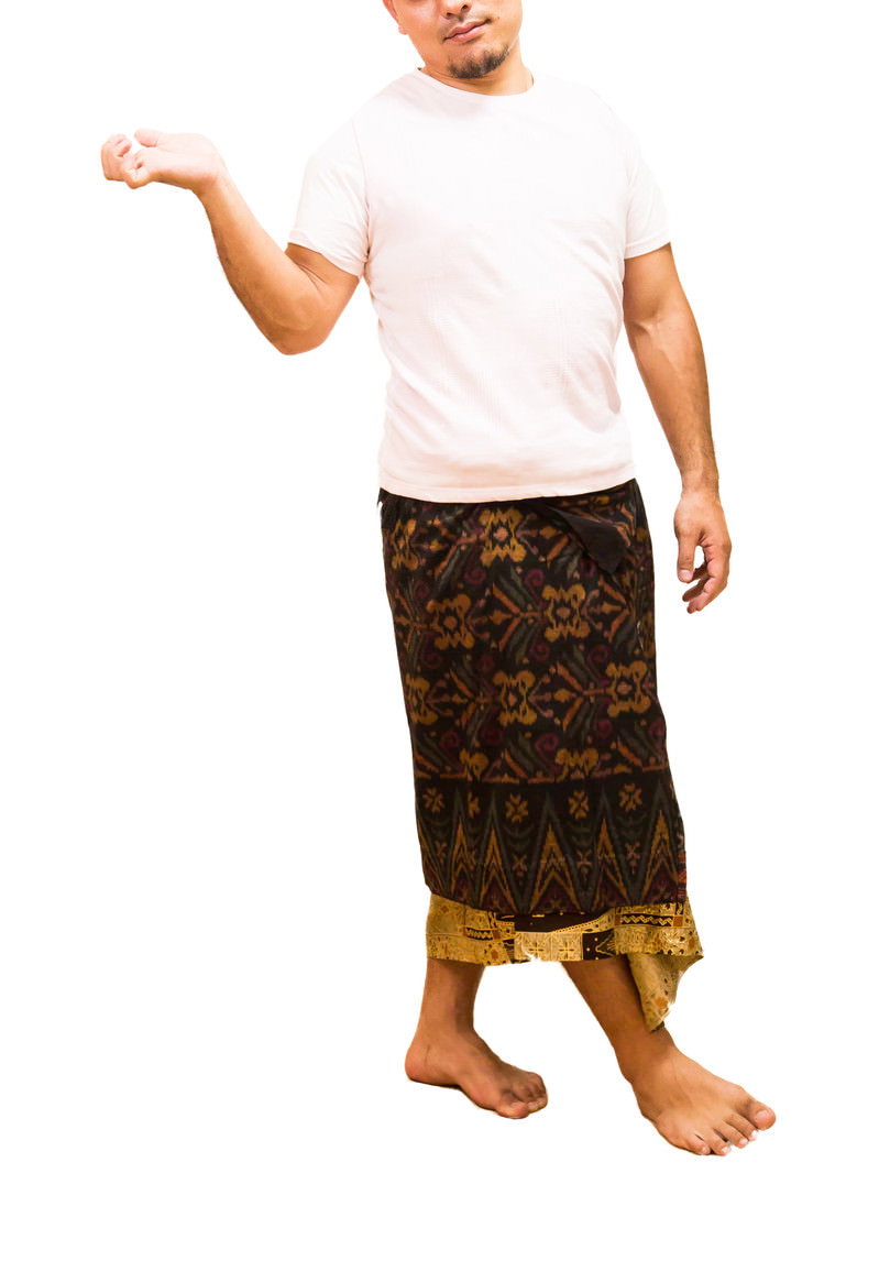 A man in a white t-shirt and brown traditional salon stands with one hand extended, appearing disinterested.