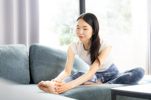 ソファに座って微笑む白いTシャツの女性