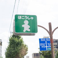 住宅街の交差点に設置された緑色の歩行者・自転車専用案内標識の写真