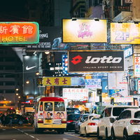 ネオン看板が並ぶ夜の香港の繁華街と渋滞する車の写真