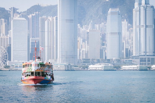 香港のビクトリアハーバーに映る高層ビル群と観光フェリー