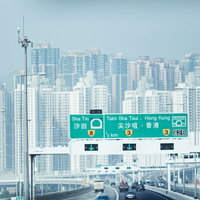 香港の高速道路を走行中に見える密集したマンション群と道路標識の写真