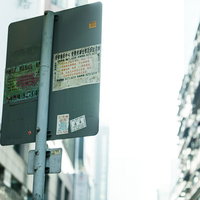 標識の看板裏まで広告が貼り付けられている香港の街中の写真