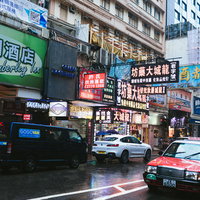 香港らしい看板と建物が密集する雑多な街並みと赤いタクシーの写真