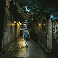 小雨が降る香港の下町路地裏を歩く歩行者の日常風景の写真