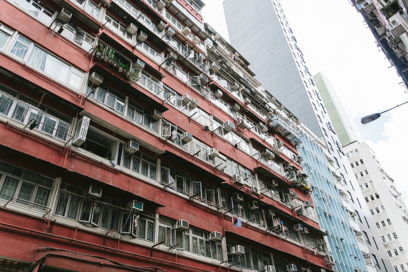 赤い外壁の古い団地と白い高層ビルが並ぶ香港の街