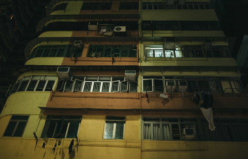 香港の雑居集合住宅、窓から漏れる黄色い照明と洗濯物