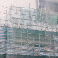 香港の建築現場で組まれている竹の足場と作業員の写真