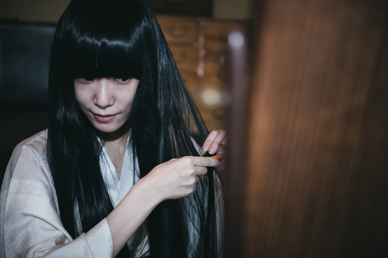 鏡の前で黒髪を櫛で梳く着物姿の女性［モデル：緋真煉］