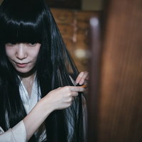 鏡に映る黒髪を櫛で梳く着物姿の女性の写真