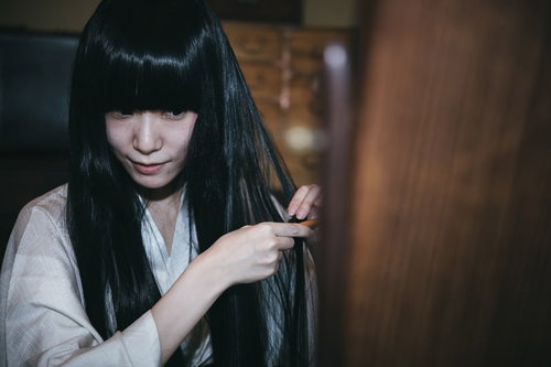 鏡に映る黒髪を櫛で梳く着物姿の女性