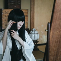 和室の鏡の前で櫛を使って髪をとかす黒髪の女性の写真