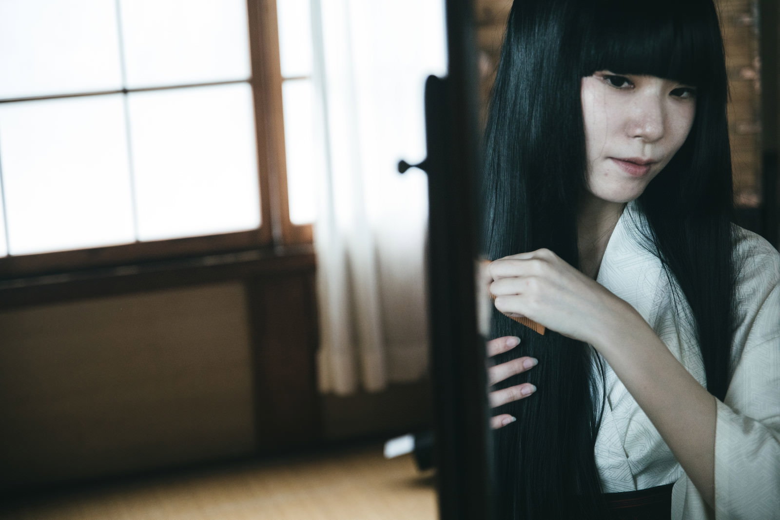和室の鏡の前で黒髪を櫛で梳く女性［モデル：緋真煉］