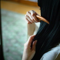 黒髪に櫛をとおす後ろ姿の女性の昭和レトロな和風シーンの写真