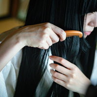 和室で長い黒髪に櫛をとおす白装束の女性の不気味な姿の写真