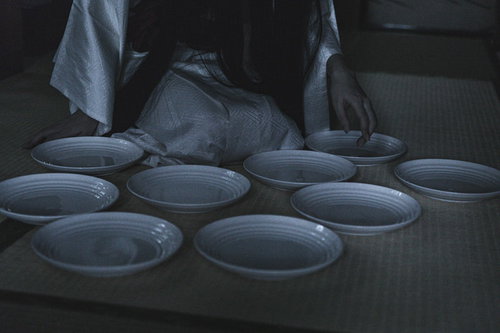 消灯時間を過ぎても皿が一枚足らない状態で床に並べられた皿を数える女性