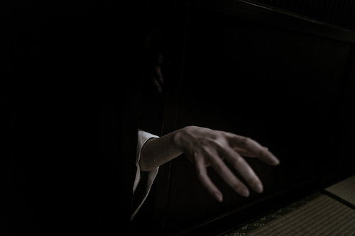 暗い隙間から伸びる白い手のホラー表現と怨念の演出