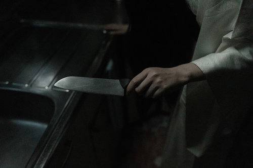 暗い背景で包丁を握る手のホラー・サスペンス