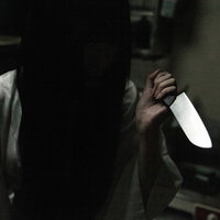 暗い空間で包丁を握りしめるシャイな女性の恐怖表現の写真