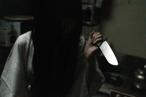 暗い空間で包丁を握りしめるシャイな女性の恐怖表現