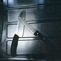 薄暗いキッチンのシンク横に置かれた包丁二本の写真