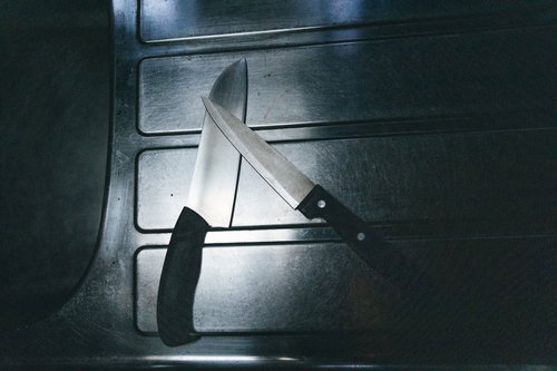 薄暗いキッチンのシンク横に置かれた包丁二本