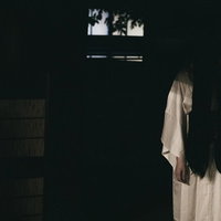 暗闇の中から下を向いた長い黒髪の女性の霊の写真