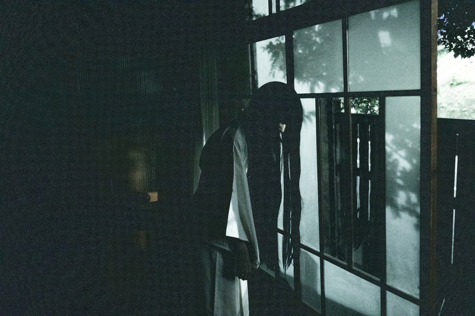 薄暗い古民家の窓辺に立つ女性のシルエット［モデル：緋真煉］