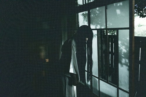 うらめしや～古民家の窓辺に立つ女性のシルエット