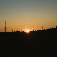 河川敷から望む日の出と送電線のシルエット風景の写真