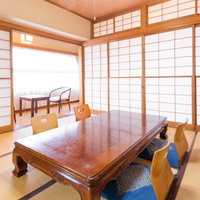 茶色い木製テーブルと青いクッション椅子がある和室の客室の写真