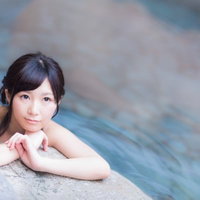 温泉の湯船の縁で寛ぐ女性、穏やかな表情で入浴の写真