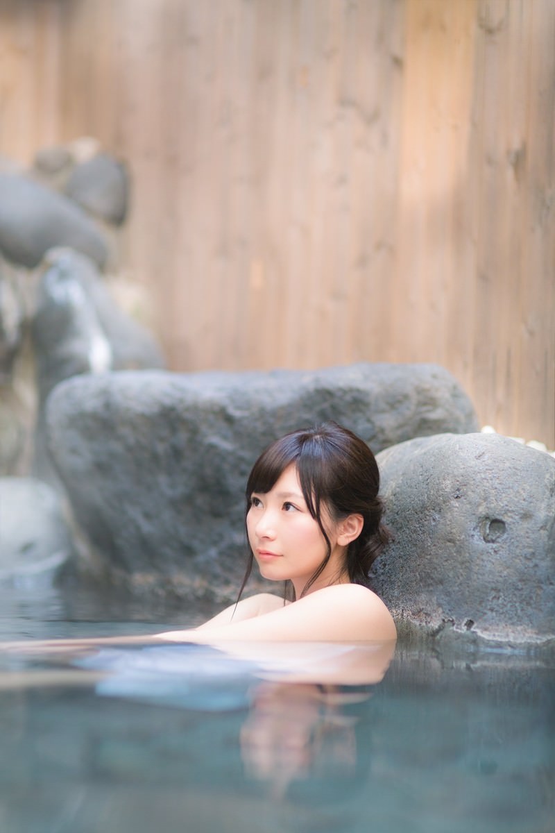 露天風呂に浸かり肩を出した女性が振り返り、水面に映り込む光景［モデル：伊東里織］