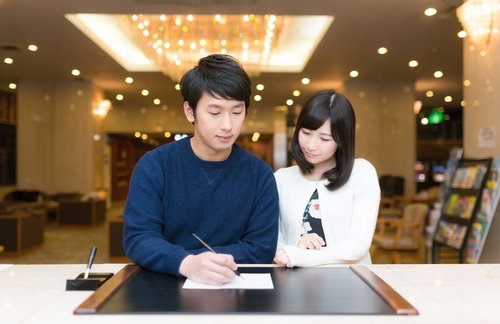 伊東温泉旅館のロビーでチェックインするカップル