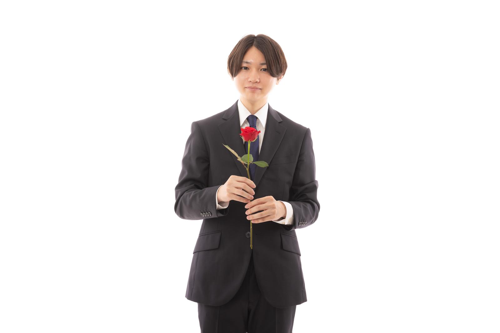 黒いスーツを着た男性が赤い薔薇を持って告白している［モデル：SHUN］