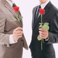赤いバラの花を持って告白する会社員の男性二名の写真
