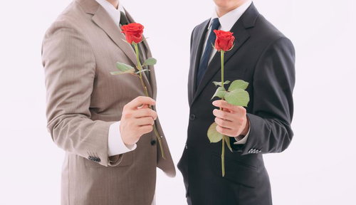 赤いバラの花を持って告白する会社員の男性二名