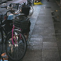 福富町商店街の歩道に並ぶピンク色とグレー色のカゴ付き自転車の写真