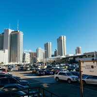 高層ビル群を背景にしたショッピングセンターの駐車場の写真