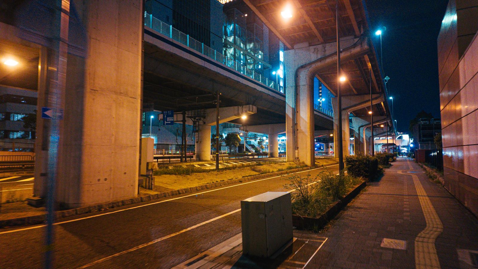 深夜の高架下に続く歩道と街灯