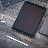 木目調テーブルに置かれたタブレット端末とスマートフォンの写真