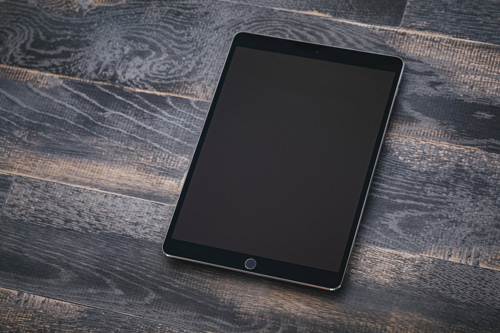 木目テーブルの上に置かれた画面オフのiPad