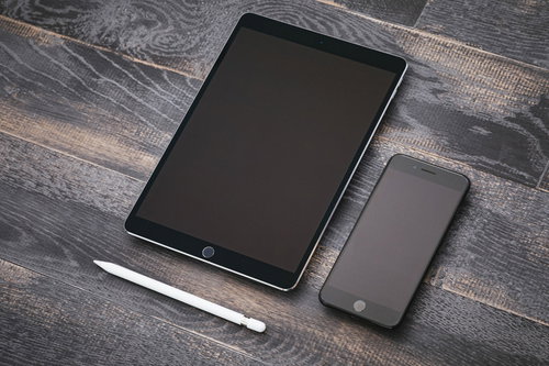 木目のテーブルに並べたiPadとiPhoneのガジェット配置