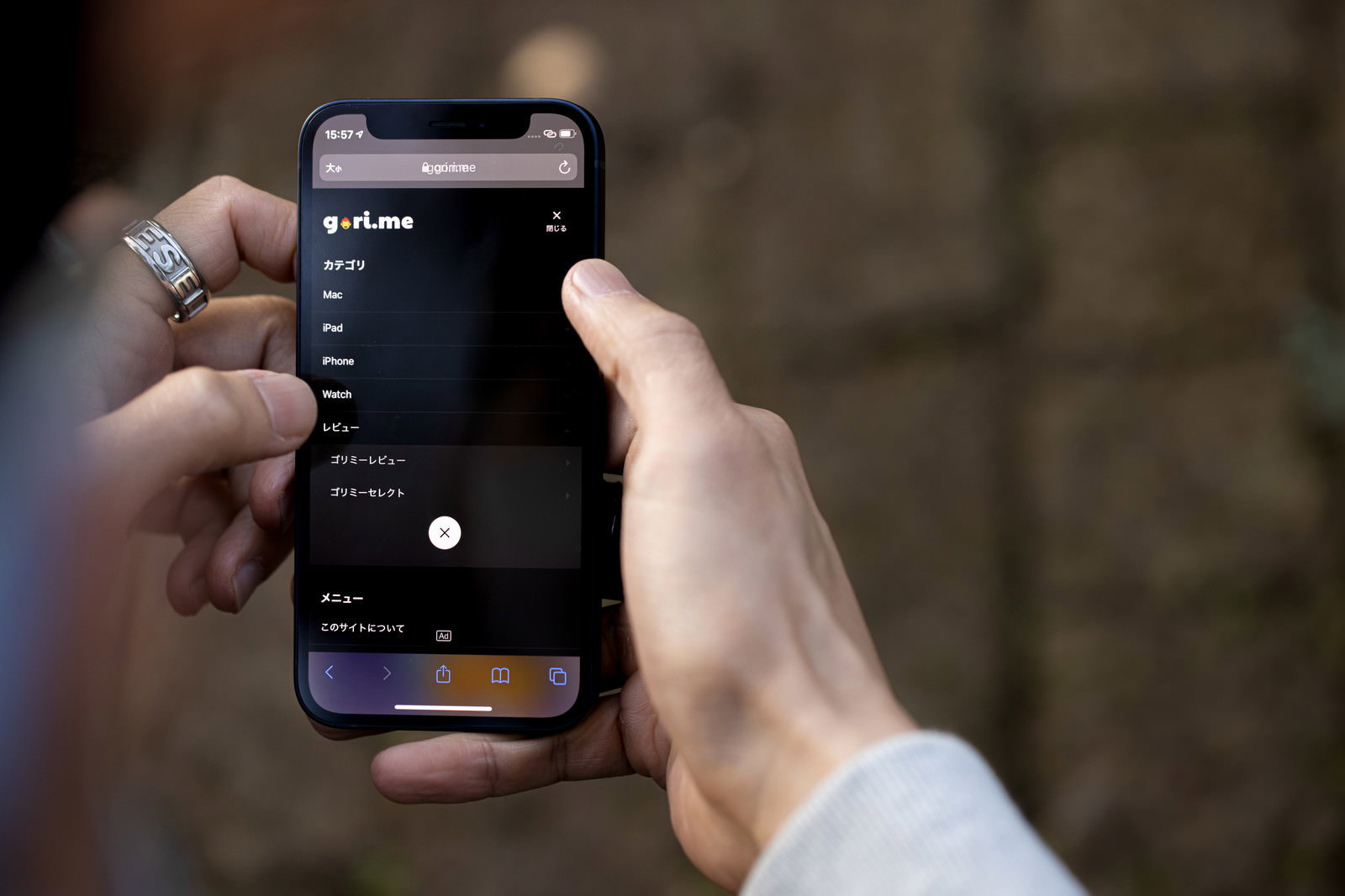 白いシャツを着た人が両手でiPhone12を持って操作している