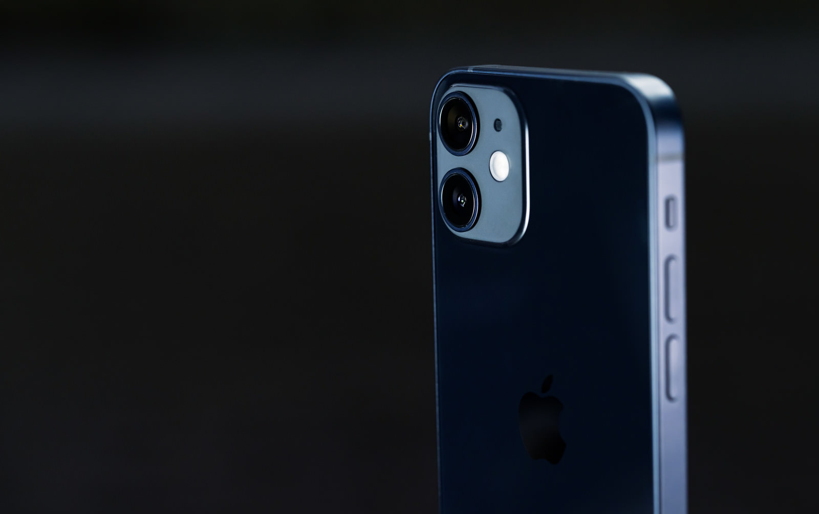 暗い背景にネイビーブルーのiPhone 12が浮かび上がっている