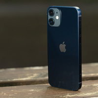 木目調の台に自立したiPhone12のリアカメラの写真