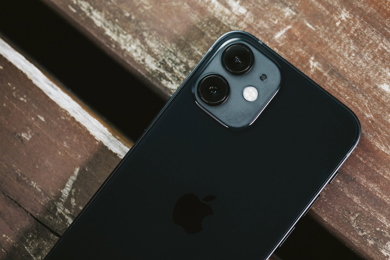 木製テーブルの上に置かれたiPhone 12のリアカメラ部分