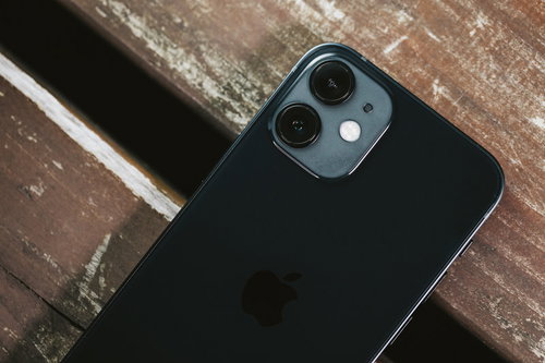 木製テーブルの上に置かれたiPhone 12のリアカメラ部分