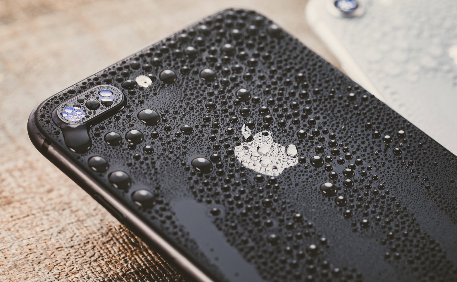 水滴が付いた黒いiPhoneの背面とリンゴのロゴ